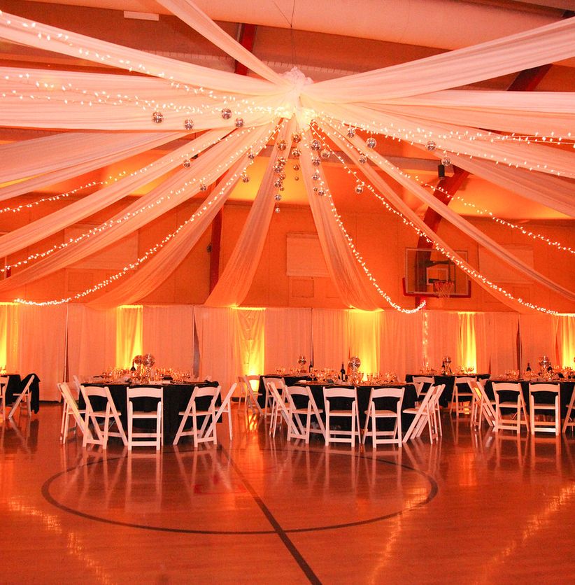 Wedding reception room with draped ribbons and warm uplighting